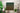 Green-to-gold gradient typography artwork displaying the full Jamaica National Anthem in bold lettering for Caribbean-inspired wall décor with text in a room with plants and a ladder